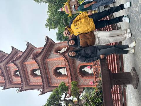       Three people posing in front of a stone tower with ornate carvings.
  