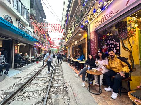       A lively street scene with cafes and decorations, with a railway track running through.
  