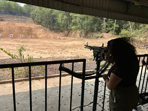       Person at a shooting range with a machine gun aimed at targets.
  