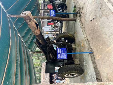       Large artillery piece displayed under a green canopy.
  