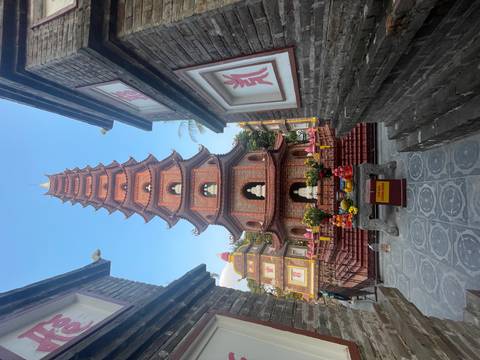       Pagoda framed by two smaller buildings with offerings at the base.
  