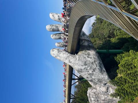       Famous Golden Bridge supported by giant stone hands with visitors.
  