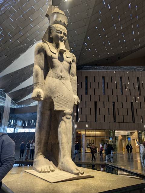       Large stone statue in a modern museum setting.
  