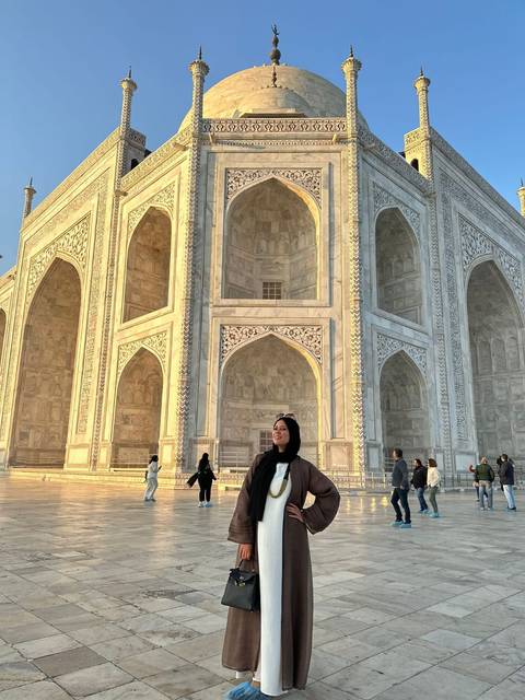 Tourist standing near the famous white marble mausoleum.