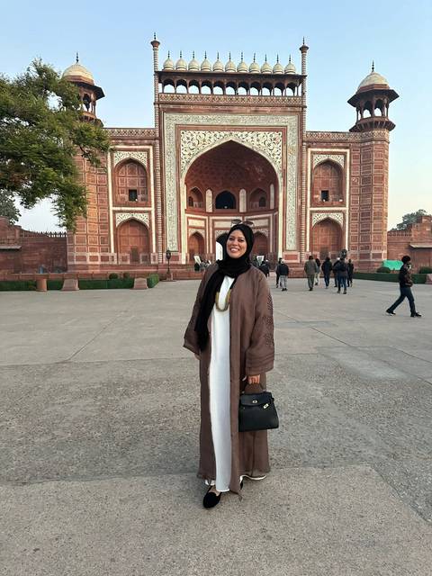 Visitor posing in front of a large red sandstone gate.