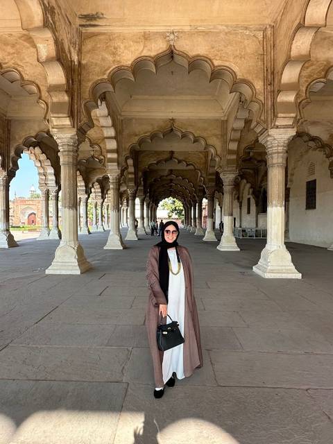 Person standing inside an ornate historic building with arches.