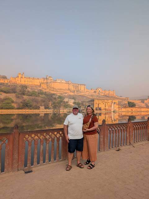 Couple standing in front of the Amber Fort by a lake.