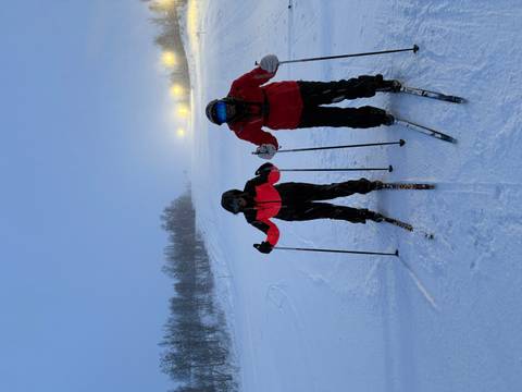 Two people in ski gear standing on a snowy slope.