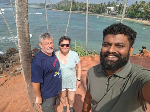 Three people taking a selfie with a scenic beach background.