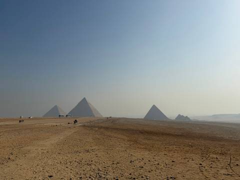 Panoramic view of the Pyramids of Giza under a clear blue sky.