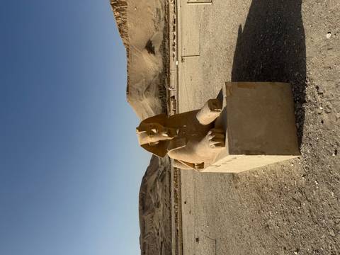 Sphinx statue under a clear sky with desert background.