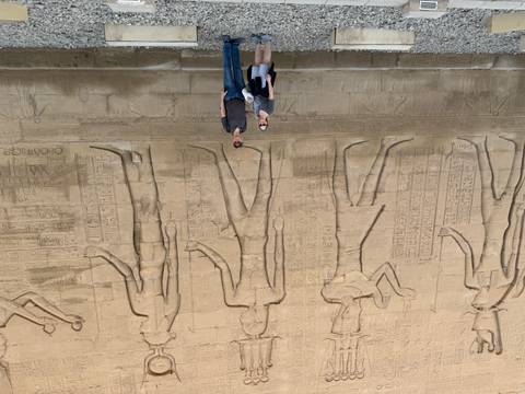 A couple standing in front of ancient hieroglyphics.