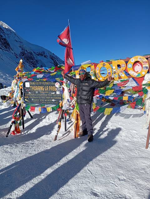       Two people with prayer flags at a snowy mountain pass, celebrating.
  