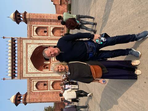 Couple posing in front of a red and white building with intricate designs.