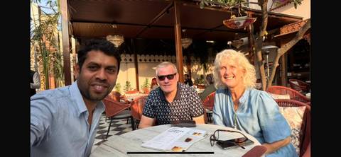 Three friends sitting around a table at an outdoor cafe.