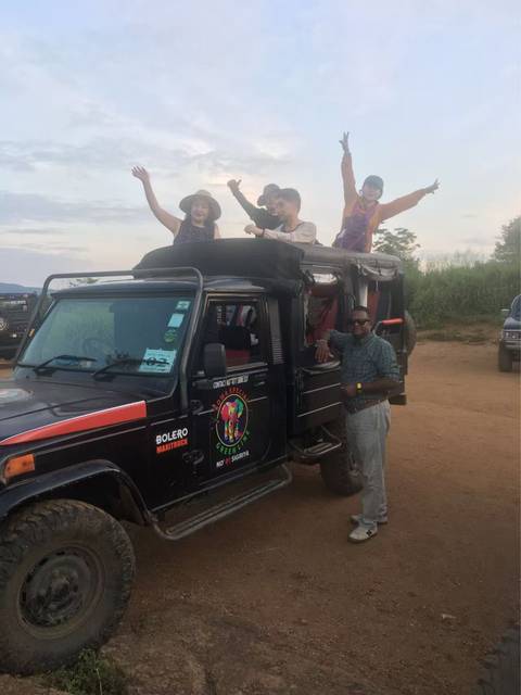 Four people standing on the open top of a safari vehicle.