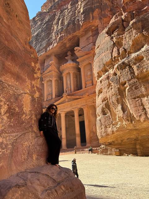 A person posing beside the Al-Khazneh (The Treasury) in Petra, Jordan.