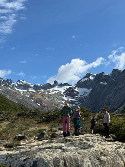 Three people posing in front of snow-capped mountains.