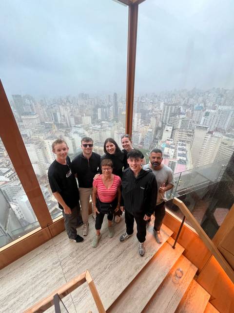 A group of people posing inside a high-rise building with a view of the city.
