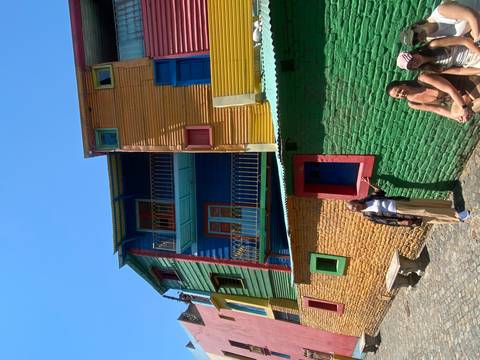 Colorful houses in Caminito with people interacting.