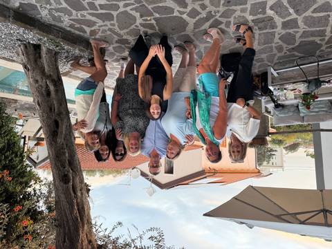 Group of people gathered on a patio with a pool, trees, and houses in the background.