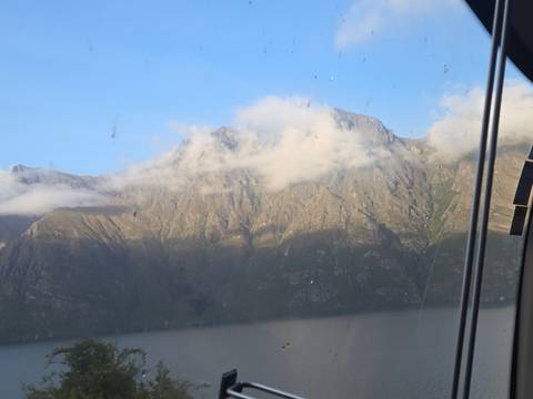 Mountains covered in clouds seen through a window with droplets.