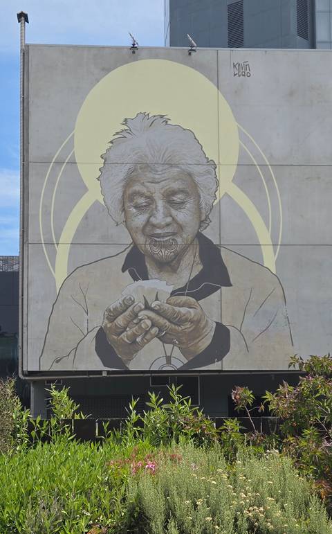 Artistic mural of an elderly person holding paper, on a wall.
