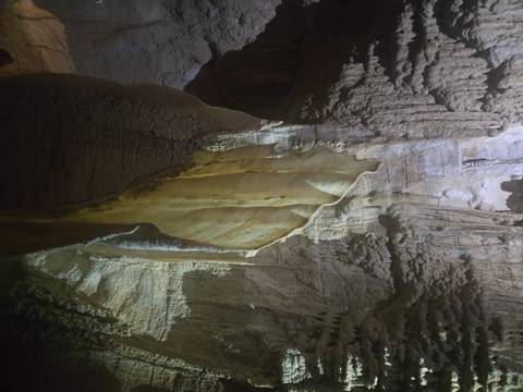       Cave with stalactites and rock formations illuminated by artificial light.
  