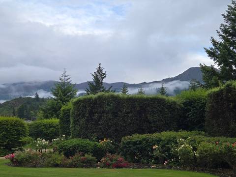 Landscape with greenery, mountains, and clouds in the background.