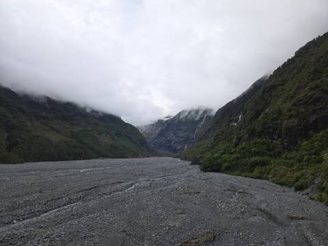 A wide river flowing through a deep valley with surrounding foliage.