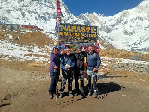 A group of people posing with a sign at Annapurna Base Camp.