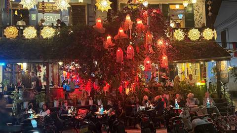 People dining outside at night with decorative lights.
