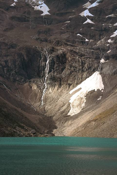       A rugged mountainous terrain with snow patches and rock formations.
  