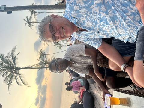 Two men sitting at an outdoor venue by the sea, enjoying the sunset.