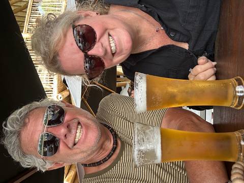 A couple enjoying a drink outdoors with beer glasses on the table.