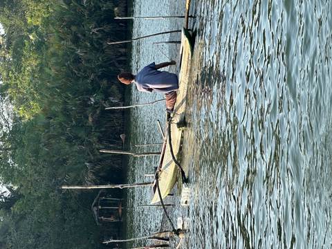       A man paddling a traditional canoe on a calm river.
  