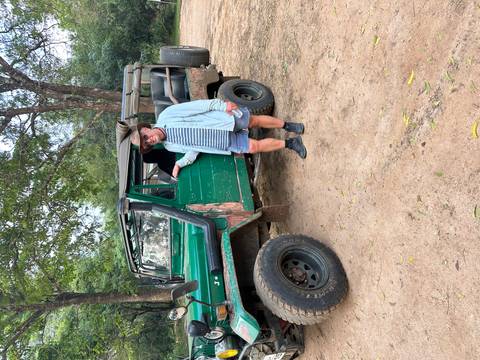       A man leaning on a rugged jeep in a natural setting.
  