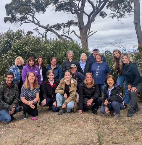       Group of people posing in an outdoor setting with bushes in the background.
  