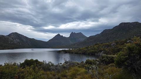       Lake surrounded by mountains under an overcast sky.
  