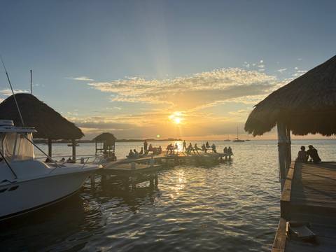 People enjoying a sunset view from a dock on the water.