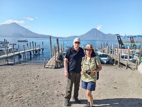       A couple posing by Lake Atitlán with mountains in the background.
  