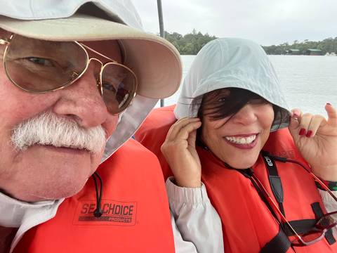       Couple in life jackets enjoying a boat ride.
  