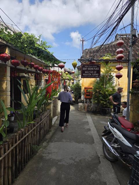 Tourists walking through a scenic traditional street with lanterns.