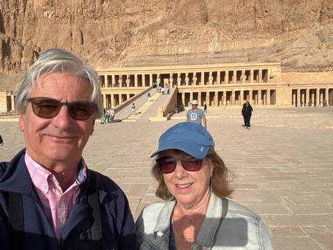 Couple taking a selfie in front of a large stone structure.