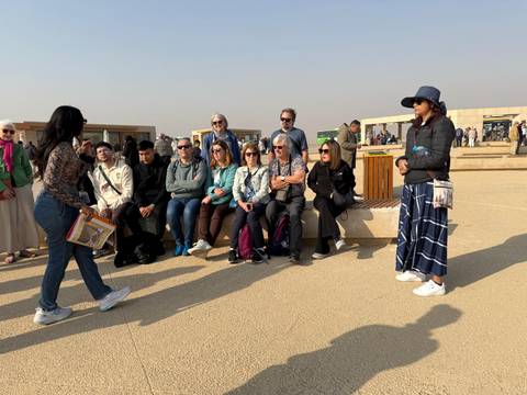 Tour group sitting at an outdoor location with a guide talking.