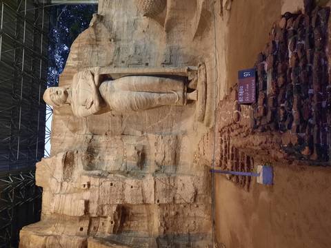       Ancient rock carving of a standing Buddha statue
  