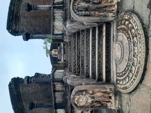       Ancient architectural site with a Buddha statue on top of stairs
  