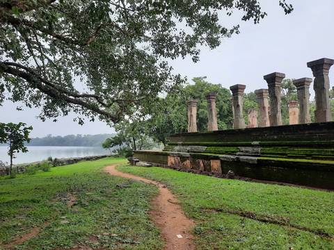       Ancient ruins by a lakeside surrounded by greenery
  