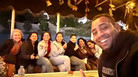 Friends enjoying a boat ride on a river while the sun sets, possibly in Aswan, Egypt.