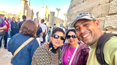 Group selfie with ancient rock structures in the background at a historical site in Luxor, Egypt.